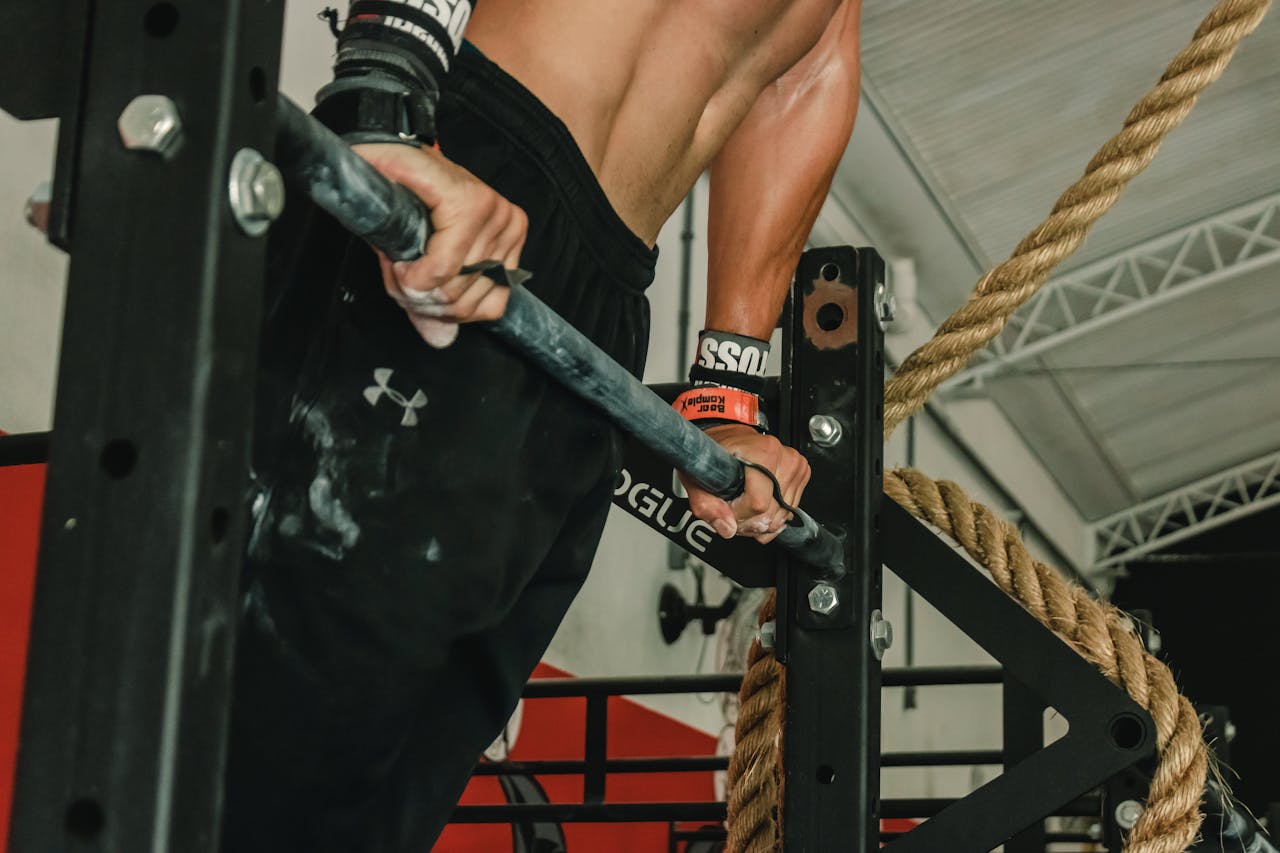 A muscular man performing a pull-up exercise indoors, showcasing strength and fitness.